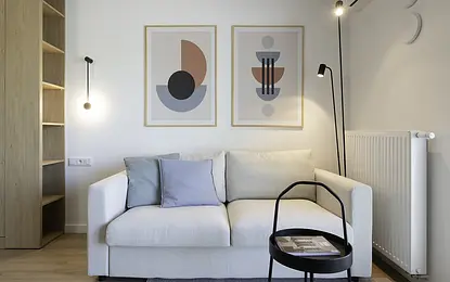 Wnętrze salonu w stylu skandynawskim z jasną sofą i drewnianymi detalami.