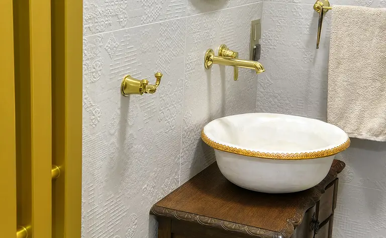 Wnętrze łazienki z umywalką, złotymi detalami i rustykalnym stylem.