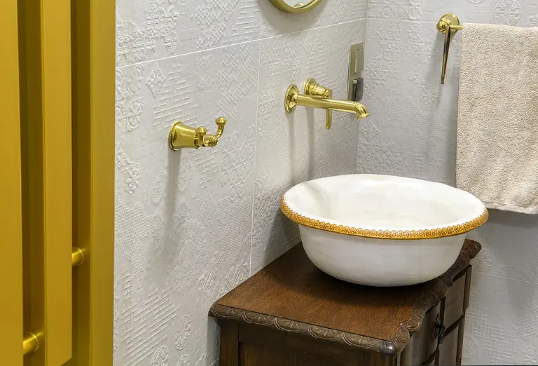 Wnętrze łazienki z umywalką, złotymi detalami i rustykalnym stylem.