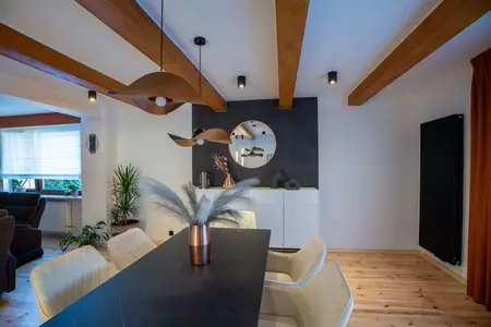 Jadalnia z drewnianym stołem, białymi krzesłami i nowoczesnymi lampami w stylu industrialnym.