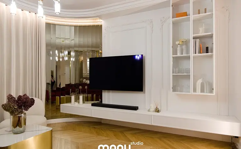 Wnętrze salonu z białymi meblami, drewnianą podłogą i lustrem.