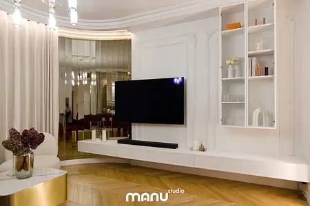 Wnętrze salonu z białymi meblami, drewnianą podłogą i lustrem.