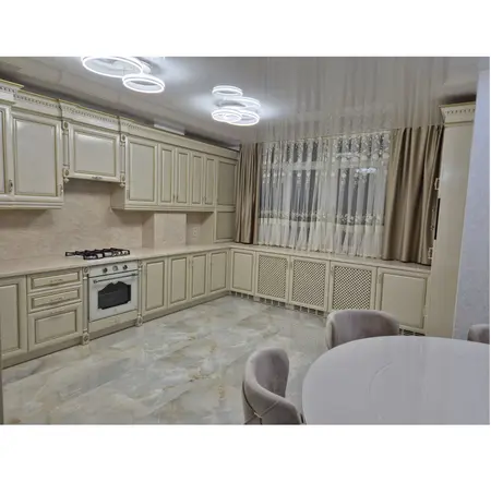 Kuchnia z jasnymi meblami, marmurową podłogą i zasłonami w stylu quiet luxury.