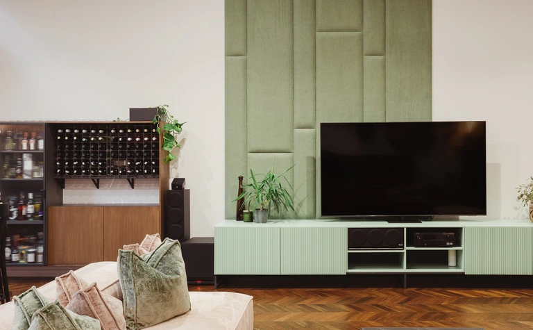 Wnętrze salonu w stylu dopamine decor, eklektycznym i rustykalnym z zieloną ścianą.