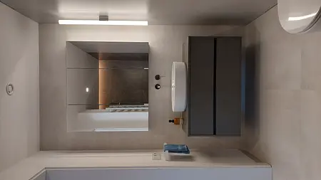 Wnętrze łazienki z minimalistycznym designem, szarymi płytkami i nowoczesną umywalką.