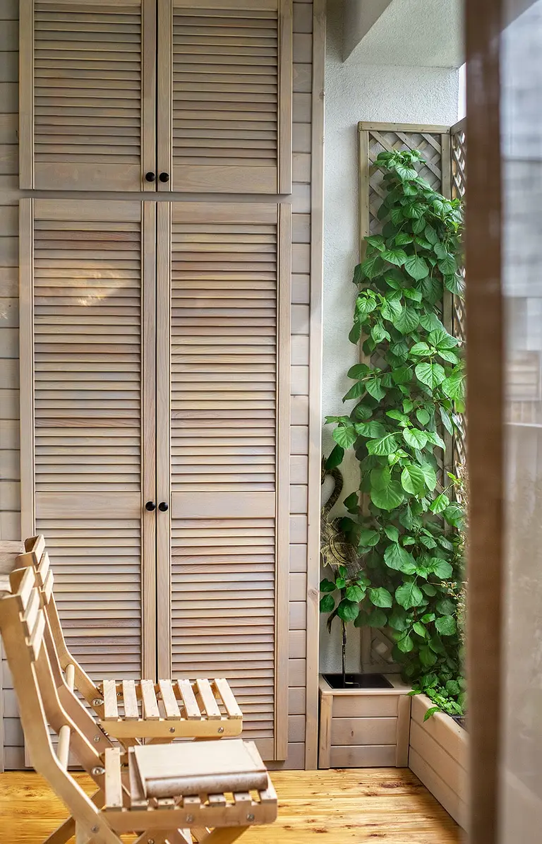 Balkon w stylu boho z drewnianymi meblami i roślinnością