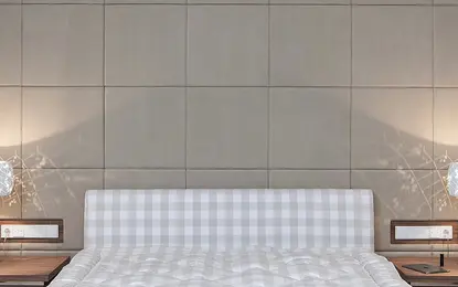 Sypialnia z eklektycznym wystrojem, szare ściany oraz białe łóżko z wzorem w kratkę.