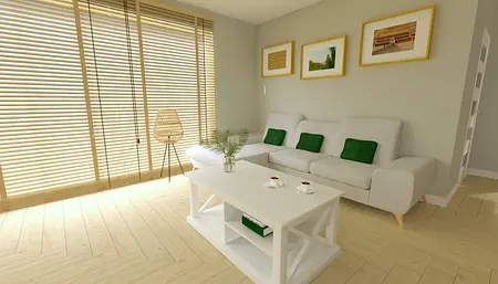 Wnętrze salonu z białą sofą, zielonymi poduszkami i drewnianym stolikiem.