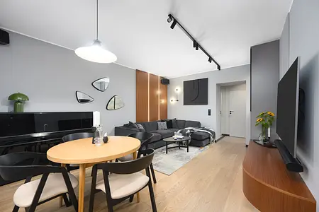 Wnętrze salonu w stylu industrialnym z czarną sofą, drewnianymi akcentami i nowoczesnym oświetleniem.