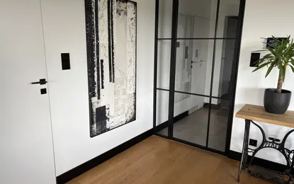 Przedpokój z czarnymi elementami, minimalistycznymi detalami i nowoczesnym wystrojem.