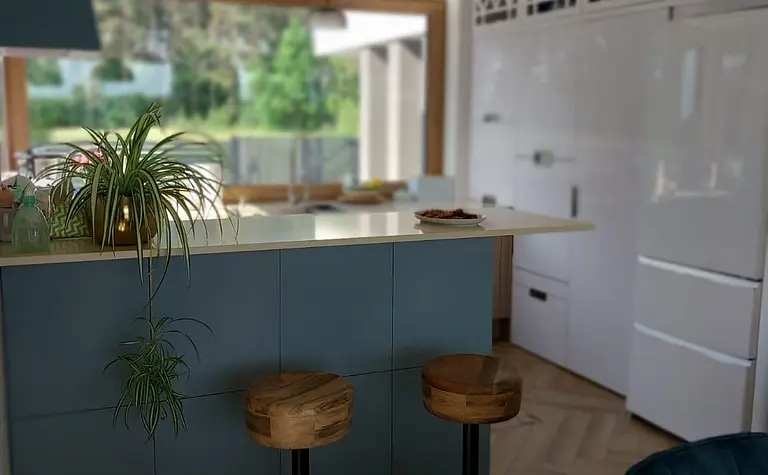 Kuchnia w stylu eklektycznym z niebieskimi meblami i drewnianym blatem.