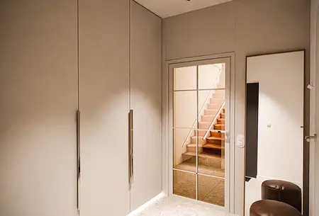 Garderoba w stylu nowoczesnym z beżowymi meblami i lustrem