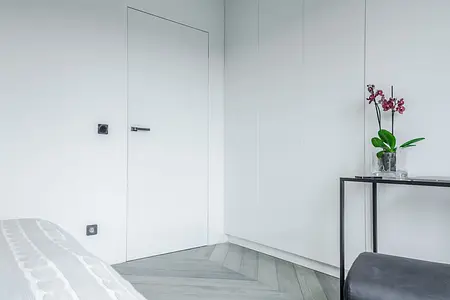 Minimalistyczne wnętrze z białymi ścianami i storczykiem w doniczce.