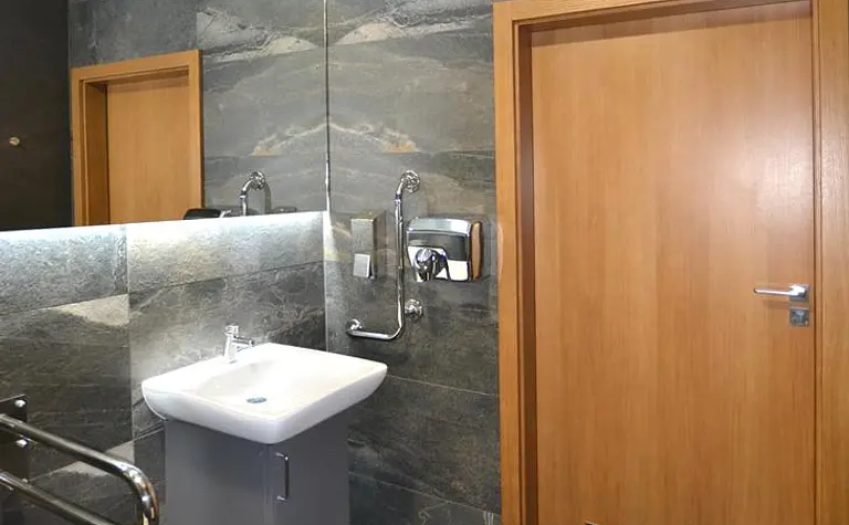 Nowoczesna łazienka z minimalistycznymi detalami, szare płytki, drewniane elementy.