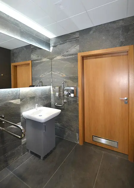 Nowoczesna łazienka z minimalistycznymi detalami, szare płytki, drewniane elementy.