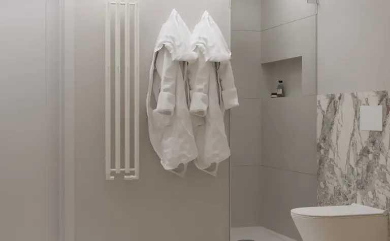 Łazienka w stylu japandi i minimalistycznym z białymi szlafrokami i marmurową płytką.