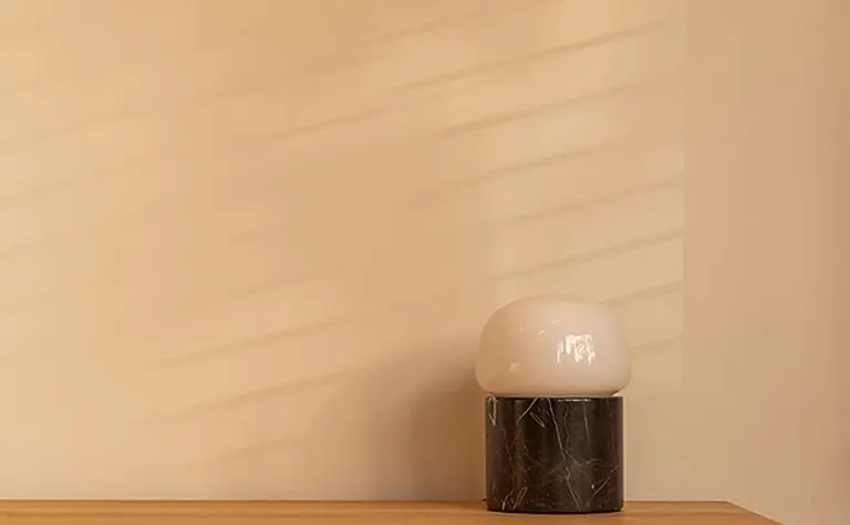 Minimalistyczne biuro z drewnianym biurkiem i nowoczesną lampą.