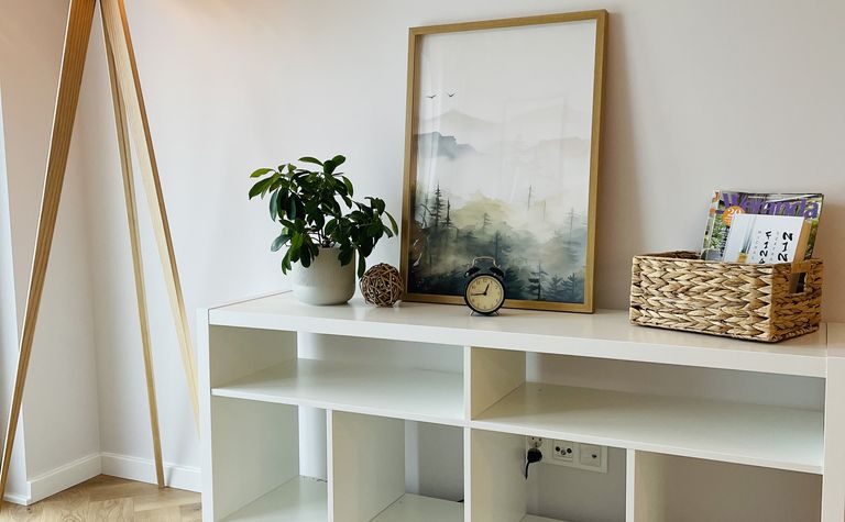 Minimalistyczne wnętrze z białym meblem, drewnianą lampą i rośliną
