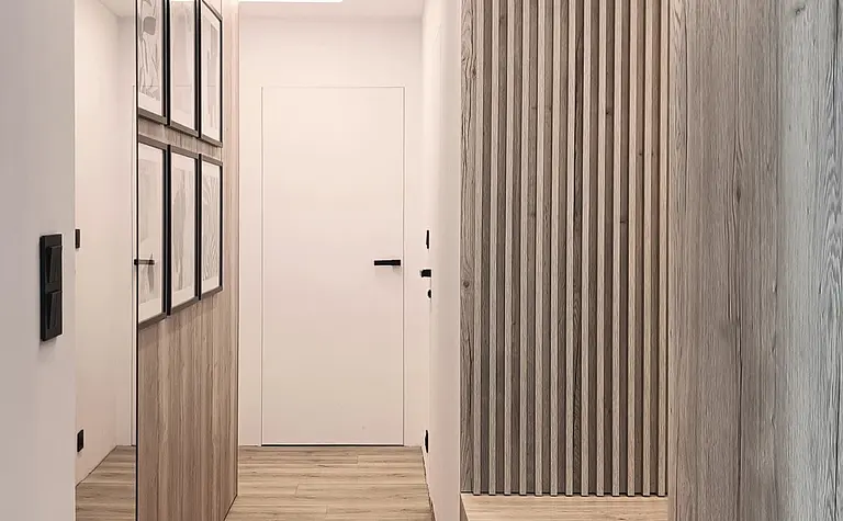 Przedpokój w stylu japandi z drewnianymi elementami i nowoczesnym oświetleniem.