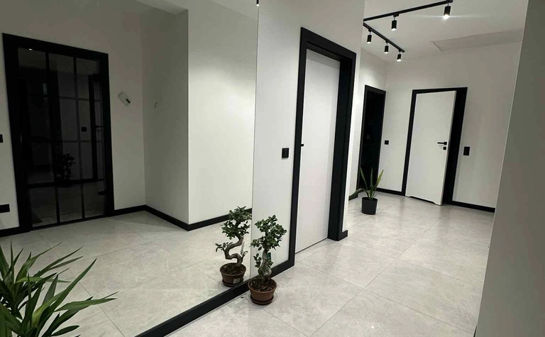 Przedpokój w stylu industrialnym i nowoczesnym z białymi ścianami i roślinami.