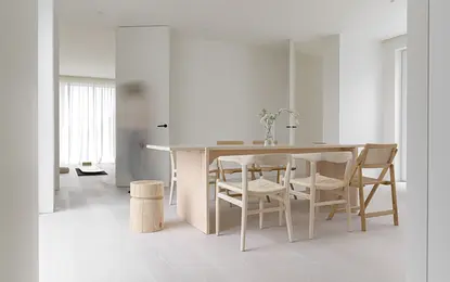 Wnętrze jadalni w stylu minimalistycznym, z drewnianym stołem i białymi krzesłami