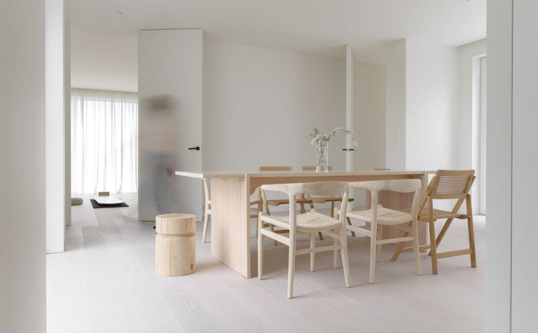 Wnętrze jadalni w stylu minimalistycznym, z drewnianym stołem i białymi krzesłami