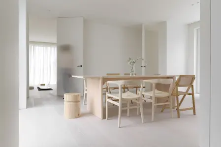 Wnętrze jadalni w stylu minimalistycznym, z drewnianym stołem i białymi krzesłami