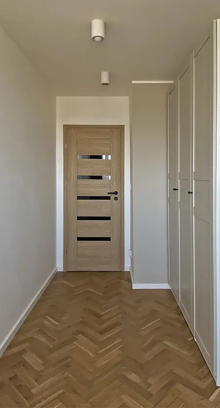 Przedpokój w stylu eklektycznym z drewnianą podłogą i białymi meblami.