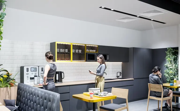 Wnętrze kuchni industrialnej z czarnymi meblami i żółtymi akcentami.