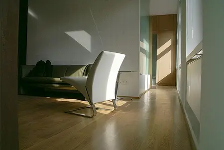 Wnętrze salonu w stylu eklektycznym z białym fotelem, brązową kanapą i dużą ilością światła.
