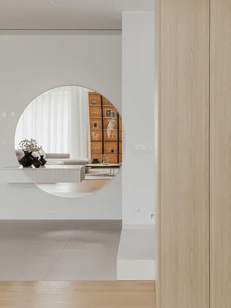 Wnętrze w stylu japandi z minimalistycznymi meblami i dużym lustrem okrągłym.