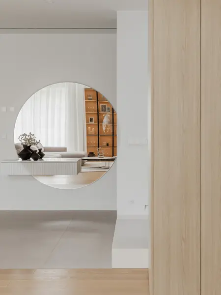 Wnętrze w stylu japandi z minimalistycznymi meblami i dużym lustrem okrągłym.