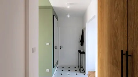 Przedpokój w stylu boho i minimalistycznym z zieloną ścianą i czarno-białą podłogą.