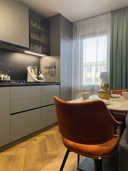 Nowoczesna kuchnia z szarymi meblami i brązowymi detalami, minimalistyczny design.