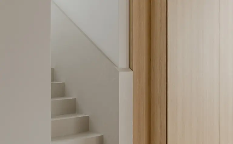 Przedpokój w stylu japandi z drewnianymi schodami i minimalistycznym wystrojem.