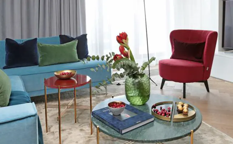 Wnętrze salonu w stylu minimaluxe i quiet luxury z niebieską sofą.