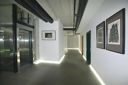 Współczesny korytarz z industrialnymi detalami i minimalistycznym oświetleniem.