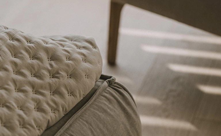 Wnętrze z beżowym fotelem i poduszką w stylu minimaluxe, nowoczesnym, quiet luxury, współczesnym.