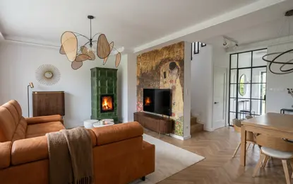 Wnętrze salonu z pomarańczową sofą, zielonym piecem i art deco akcentami.