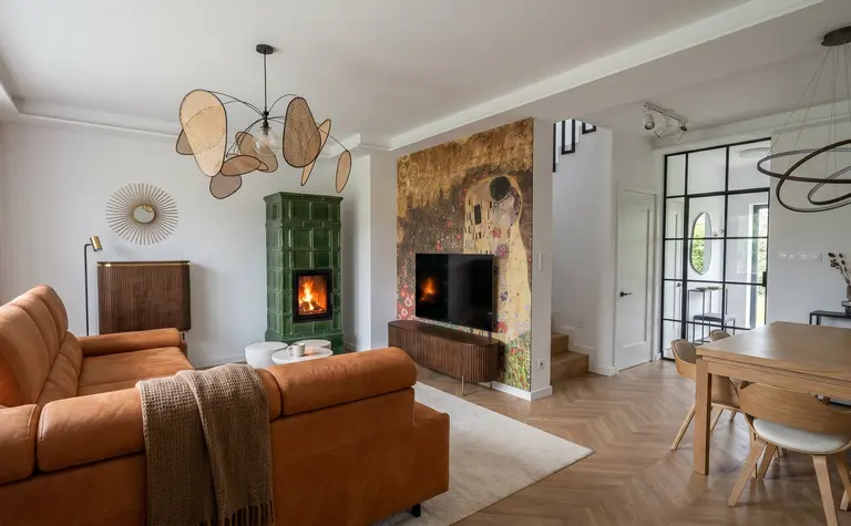 Wnętrze salonu z pomarańczową sofą, zielonym piecem i art deco akcentami.