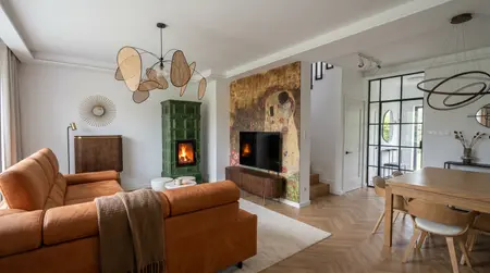 Wnętrze salonu z pomarańczową sofą, zielonym piecem i art deco akcentami.