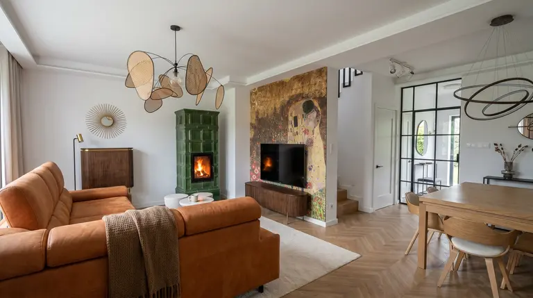 Wnętrze salonu z pomarańczową sofą, zielonym piecem i art deco akcentami.