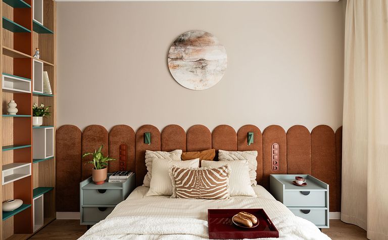 Wnętrze sypialni z brązowym wezgłowiem, zielonymi akcentami i nowoczesnym wystrojem.