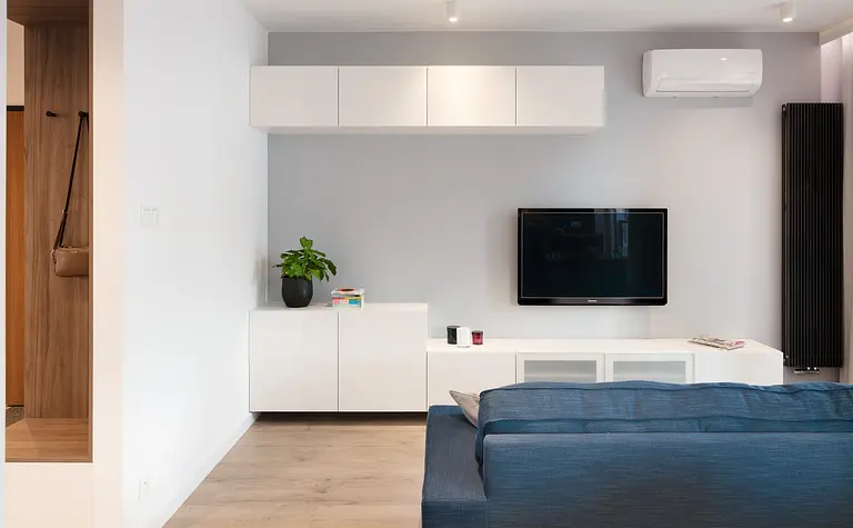 Wnętrze salonu z niebieską sofą i białymi meblami, nowoczesny design.