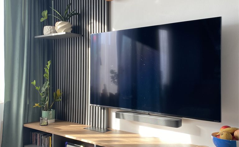 Nowoczesne wnętrze salonu z telewizorem, drewnianą półką i roślinami.