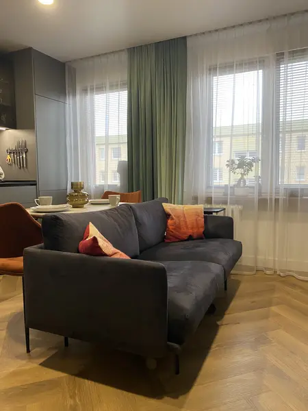 Nowoczesny salon z szarym narożnikiem i drewnianą podłogą.