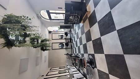Salon fryzjerski z czarno-białą podłogą, lustra i rośliny