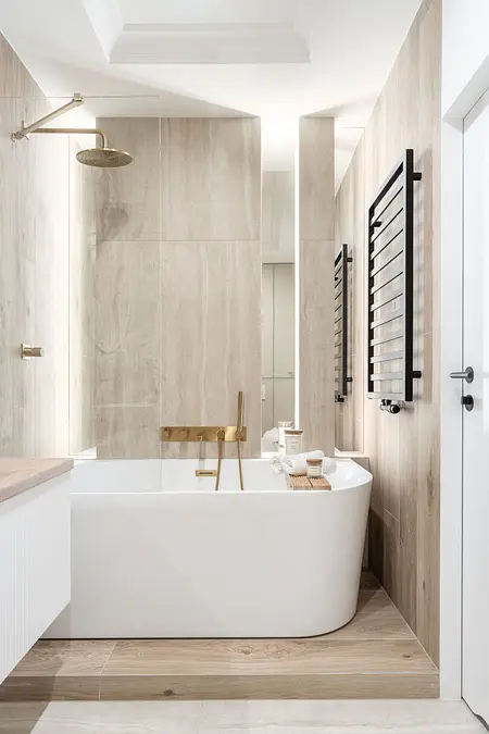 Wnętrze łazienki z wanną, drewnianymi detalami i złotymi akcentami.