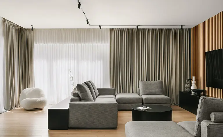Wnętrze salonu w stylu industrialnym i minimalistycznym z szarymi meblami i drewnianymi detalami.