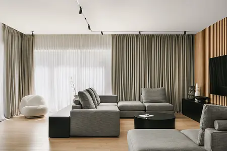 Wnętrze salonu w stylu industrialnym i minimalistycznym z szarymi meblami i drewnianymi detalami.